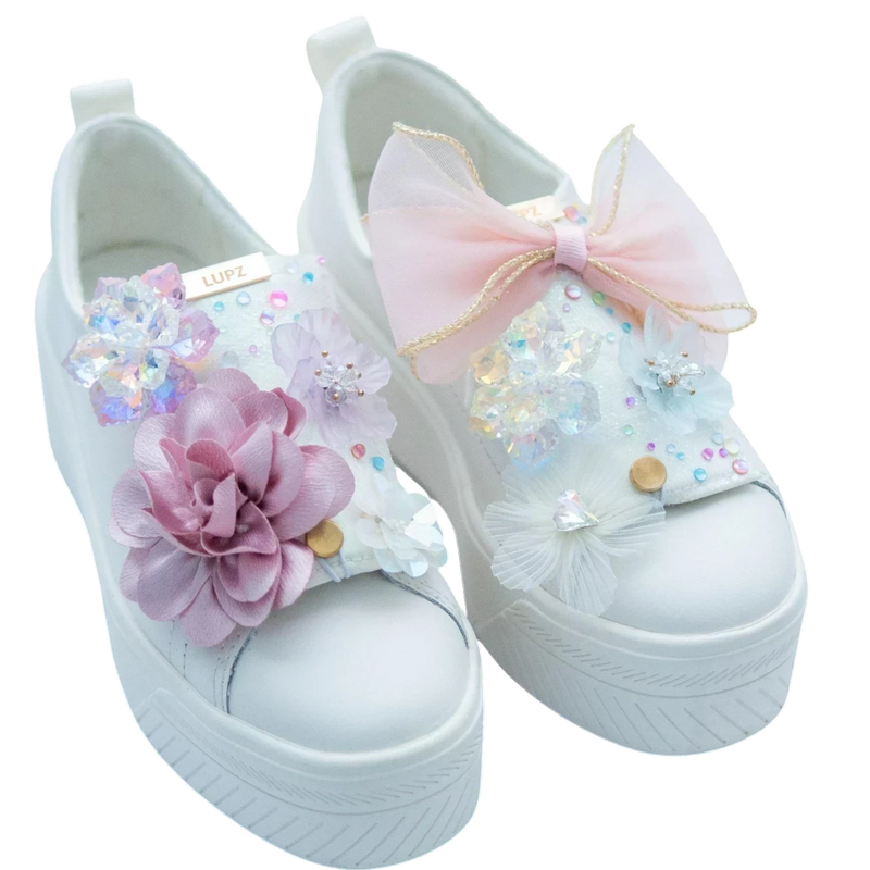 LŪPZ white platform sneakers adorned with pastel pink and purple fabric flowers, iridescent sequins, and a delicate pink bow.
